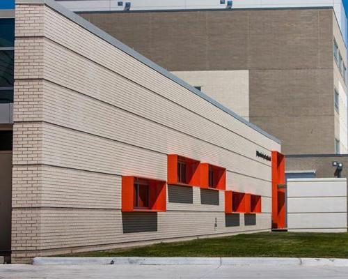 Building exterior featuring bright red metal panel window cowlings